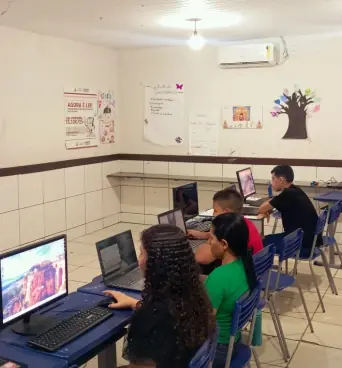 Turma em atividade prática com notebooks e computadores na sala de informática