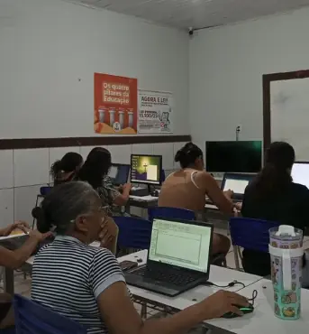 Turma adulta praticando informática em notebooks e computadores